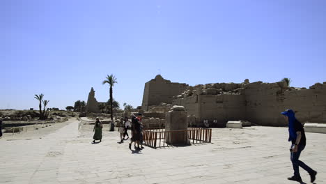 Tourists-perform-ritual-of-walk-around-stone-statue-of-frog-for-good-luck,-Karnak-Temple,-Egypt