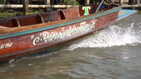 Cámara-Lenta-De-Un-Barco-Tailandés-Local-Navegando-En-El-Río-Camino-Al-Mercado-Flotante,-Cinematográfico,-De-Cerca