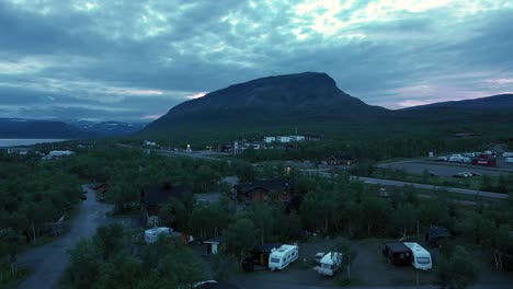 Vista-Aérea-De-La-Aldea-De-Kilpisjarvi-Y-La-Caída-De-Saanatunturi,-Sol-De-Medianoche,-En-Laponia,-Finlandia---Levantamiento,-Disparo-De-Drone