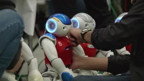 Ingeniero-Poniéndole-Un-Babero-Rojo-A-Un-Robot-Nao-En-Un-Torneo-De-Fútbol-En-Montreal