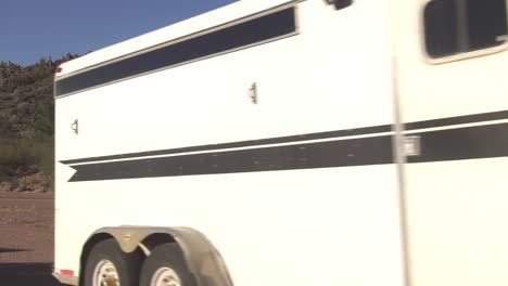 Truck-With-Trailer-Going-Past-Parked-Truck-And-Flag-Banner-Outside-Gas-Station