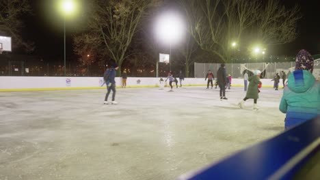 Varias-Personas-Disfrutan-Patinando-Sobre-Hielo-En-Una-Pista-De-Patinaje-Al-Aire-Libre-Durante-La-Noche