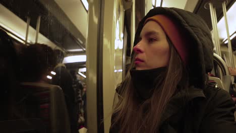 Young-caucasian-female-passenger-sitting-in-the-Paris-underground-metro-while-looking-outside-the-window-with-tram-passing