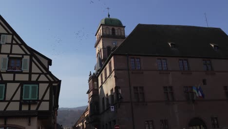 Scenic-tilt-shot-of-church-tower-building-and-half-timbered-houses-in-medieval-town-of-Kaysersberg,-France