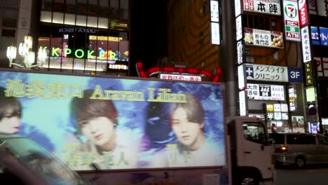 Buzzing-nightlife-with-cars-passing-by-in-Kabukicho-district,-Tokyo