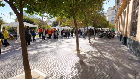 Concurrido-Mercado-Al-Aire-Libre-Bajo-Los-árboles-Con-Gente-Navegando-Por-Los-Puestos-En-Una-Avenida-Sombreada