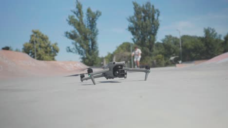 El-Dron-Despega-Del-Terreno-De-Concreto-Del-Skatepark-Mientras-El-Hombre-Hace-Caballito-En-El-Fondo