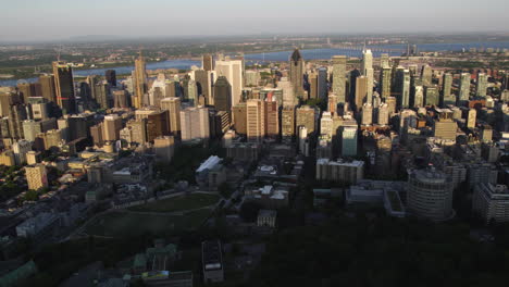 Toma-De-Seguimiento-Aéreo-Frente-Al-Centro-De-Montreal,-Puesta-De-Sol-De-Verano-En-Canadá.