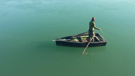 Fischer-Steht-Im-Boot,-Ruhiges-Grünes-Wasser