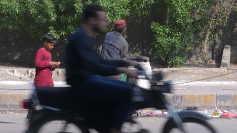 Una-Toma-De-Primer-Plano-En-Cámara-Lenta-De-Un-Recolector-De-Basura-Recogiendo-Desechos-Y-Basura-De-Un-Cubo-De-Basura-Al-Lado-De-Una-Calle-En-La-Calle-Saddar-Bazar-De-Karachi,-Pakistán