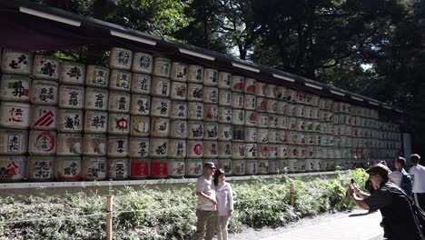 Touristen-Fotografieren-Neben-Der-Dekorativen-Wand-Aus-Sake-Fässern-Am-Meji-Schrein