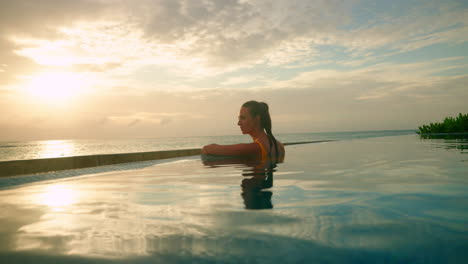 Lone-brunette-girl-with-at-the-pool-side-enjoying-beautiful-tropical-sunset-at-the-seaside