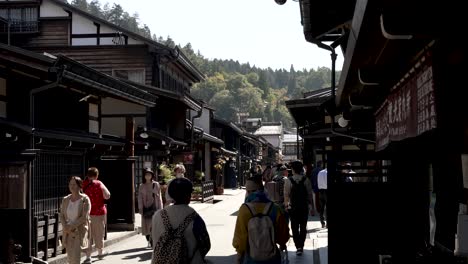 Daytime-capture-of-people-leisurely-walking-along-Sanmachi-Suji,-comprising-three-charming-streets-that-together-form-Hida-Takayama's-renowned-historic-district-in-Japan