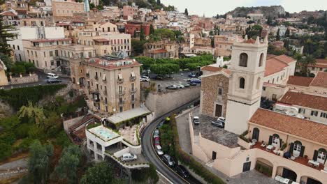 Drohne-Fliegt-Rückwärts-In-Der-Altstadt-Von-Taormina,-Die-Auf-Einem-Berg-Gebaut-Ist