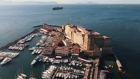 Drone-Volando-Lejos-De-Un-Fuerte-Ubicado-En-La-Costa-Del-Mar-En-Italia,-Nápoles