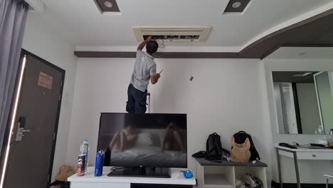 Hombre-Reparando-El-Sistema-De-Aire-Acondicionado-En-Una-Habitación-De-Hotel.