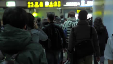 Handheld-POV-walking-behind-students-and-commuters-in-Taipei-metro-station