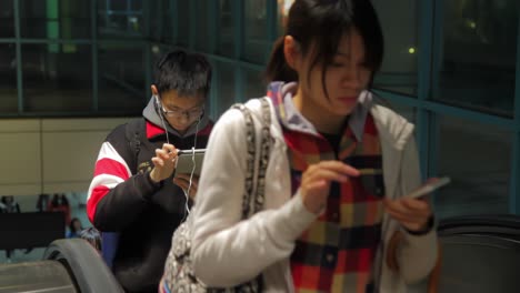 Row-of-Asian-people-coming-up-on-escalator-while-looking-at-their-screens