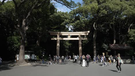 Besucher,-Die-Sich-Auf-Den-Weg-Zum-Meji-Schrein-Machen,-Kommen-Am-Großen-Hölzernen-Torii-Tor-Am-Eingang-Vorbei