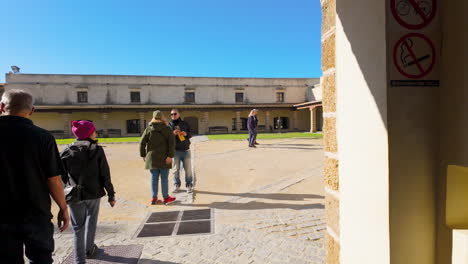 Besucher-Betreten-Ein-Historisches-Gebäude-In-Cadiz,-Spanien,-Mit-Einem-Sonnendurchfluteten-Innenhof