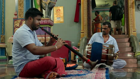 View-of-2-Indian-men-sitting-on-the-floor-playing-ritual-music-inside-Hindu-temple