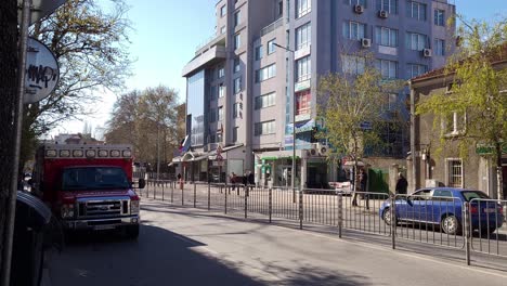 Tráfico-Ligero-Pasando-Por-Una-Ambulancia-Ford-Estacionada-En-El-Bulevar-&#39;vasil-Aprilov&#39;&#39;