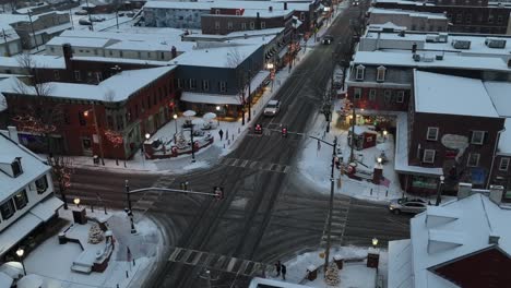 Crepúsculo-Sobre-Una-Intersección-De-Una-Pequeña-Ciudad-Cubierta-De-Nieve-Con-Luces-Festivas-Y-Una-Atmósfera-Tranquila-E-Invernal.