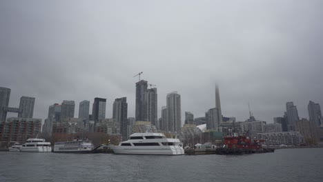 Aufnahme-Eines-Kreuzfahrtschiffes,-Das-An-Einem-Hafen-Mit-Wunderschöner-Skyline-Der-Innenstadt-Von-Toronto-An-Einem-Nebligen-Abend-In-Kanada-Geparkt-Ist