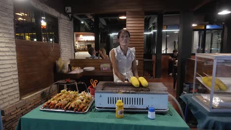 Street-vendor-cooks-corn-on-hot-grill-turning-each-cob-to-achieve-perfection