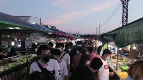 Multitud-De-Personas-Con-Máscaras-En-El-Mercado-Nocturno-De-Comida-Callejera-Al-Atardecer-En-Rayong,-Tailandia