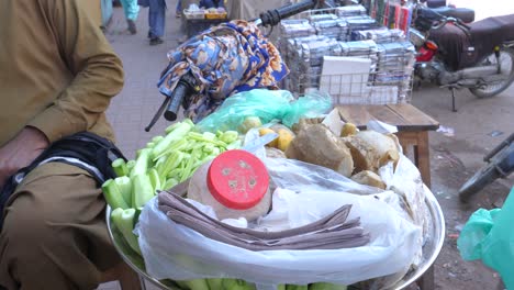 Close-up-shot-of-a-shopkeeper-selling-chaats-beside-a-busy-Saddar-Bazar-Street-during-daytime-in-Karachi,-Pakistan