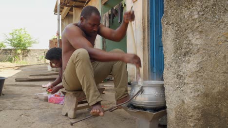 El-Hombre-Revuelve-Banku-Preparado-En-Una-Estufa-De-Carbón-Casera,-Comida-Ghanesa