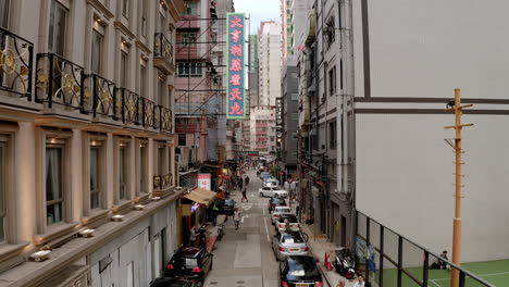 Hongkong-Tagsüber-Schmale-Gasse-Mit-Leuchtreklame,-Autos,-Menschen,-Basketballplatz,-überfüllte-Stadt,-Belebte-Straßen,-Tsim-Sha-Tsui,-Rohre,-Klimaanlagen,-Fenster,-Nahaufnahme,-Überbevölkerung,-Wirtschaftszentrum