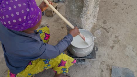 Ghanaian-black-woman-stirs-mixture-to-prepare-banku,-a-typical-ghanaian-dish