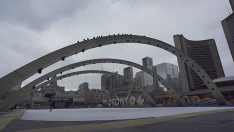 Weitwinkelaufnahme-Von-Menschen-Beim-Eislaufen-Am-Nathan-Phillips-Square-Und-Im-Rathaus-Von-Toronto-In-Kanada-An-Einem-Bewölkten-Tag