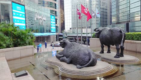 Foto-De-Dos-Estatuas-De-Toros-Y-Algunos-Visitantes-Presentes-Frente-Al-Centro-De-La-Bolsa-De-Valores-De-Hong-Kong-Durante-El-Día.