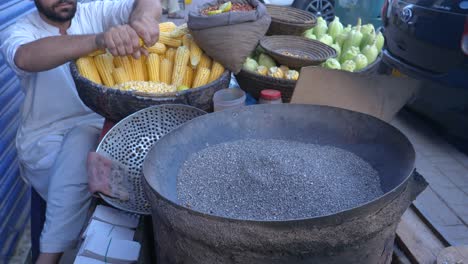 Nahaufnahme-Eines-Jungen-Mannes,-Der-Am-Abend-In-Der-Saddar-Bazar-Street-In-Karatschi,-Pakistan,-Maiskolben-Zum-Rösten-Vorbereitet