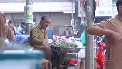 Cinematic-parallax-shot-of-a-man-with-his-roadside-stall-at-Saddar-Bazar-Street-during-daytime-in-Karachi,-Pakistan