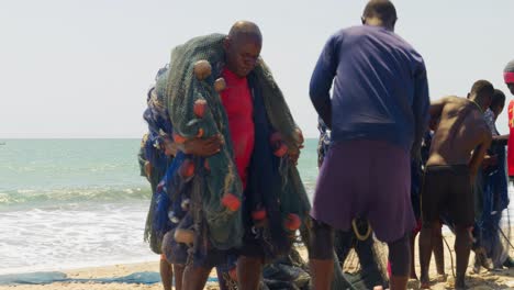 Pueblo-Africano-Llevando-Redes-De-Pesca-En-Una-Playa-En-Ghana.