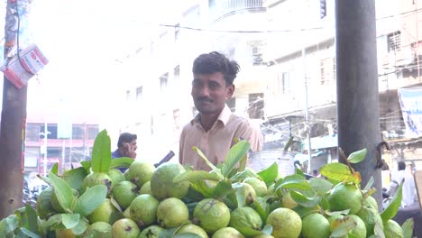 Toma-Cinematográfica-En-Cámara-Lenta-De-Un-Comerciante-Sonriente-Vendiendo-Guayabas-En-Un-Puesto-Al-Borde-De-La-Carretera-En-La-Calle-Saddar-Bazar-De-Karachi,-Pakistán.