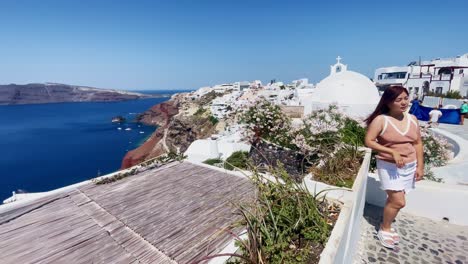 Turistas-Tomando-Fotos-En-El-Acantilado-|-Oia-Santorini-Grecia-Isla-Griega-En-El-Mar-Egeo,-Viajes-Turísticos-Vacaciones-Inmersivas-Caminatas-En-Movimiento-Junto-A-Multitudes-De-Compras-En-Acantilados-De-Mármol-Blanco-Y-Ciudad,-Europa,-4k