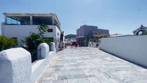 People-Passing-Along-Wide-Path-|-Oia-Santorini-Greece-Greek-Island-in-Aegean-Sea,-Travel-Tourist-Vacation-Immersive-Moving-Walk-Along-Crowds-Shopping-in-White-Marble-Cliffside-and-City,-Europe,-4K