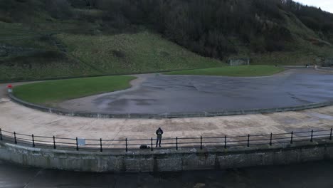 Cinematic-shot-of-a-man-flying-drone-to-get-beautiful-landscape-of-hills-covered-with-green-trees-during-a-cold-evening-in-Scarborough,-England