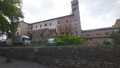 Rome-Immersive-POV:-Moving-In-Busy-Streets-to-Chiesa-Santi-Luca-e-Martina,-Italy,-Europe,-Walking,-Shaky,-4K-|-Moving-Past-An-Empty-Factory