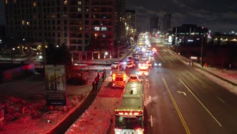 Escena-Nocturna-De-La-Ciudad-Con-Vehículos-De-Emergencia,-Carreteras-Nevadas-Y-Edificios.