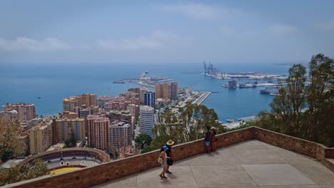 Los-Turistas-Contemplan-La-Vista-De-Los-Edificios-De-La-Ciudad-En-El-Borde-Del-Muelle-Desde-Un-Edificio-En-Las-Colinas-De-La-Ciudad-De-Málaga,-España.