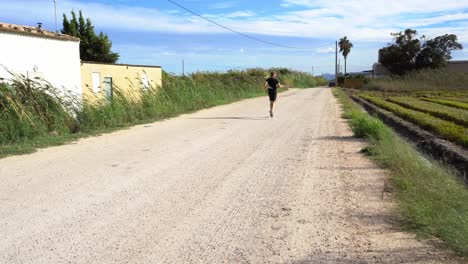 Rural-landscape,-young-man-running-and-calling-spectator-to-join-him