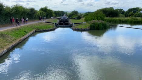 Gente-Caminando-En-Un-Día-De-Verano-Cerca-Del-Canal-Kennet-Y-Avon-En-Devizes-Inglaterra,-Clima-Soleado-Con-Cielo-Azul,-Nubes-Blancas-Y-Naturaleza-Verde,-Toma-De-4k