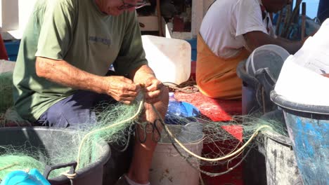 Pescador-Quitando-Mariscos-De-La-Red-De-Pesca,-De-Mano