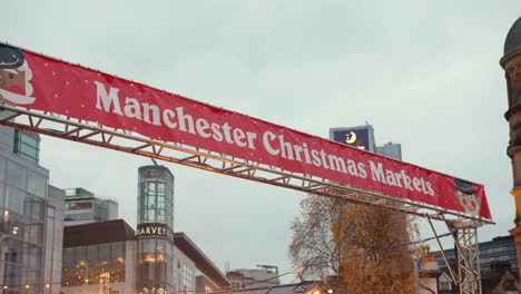 Toma-De-Paralaje-De-Un-Letrero-De-Color-Rojo-Que-Dice-&quot;mercados-Navideños-De-Manchester&quot;-En-Una-Tarde-Nublada-En-Diciembre-En-Inglaterra